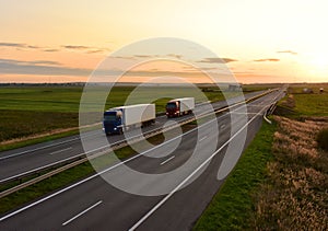 Truck with semi-trailer driving along highway on the sunset background. Goods delivery by roads. Services and Transport logistics