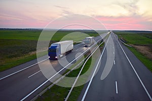 Truck with semi-trailer driving along highway on the sunset background. Goods delivery by roads. Services and Transport logistics