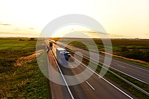 Truck with semi-trailer driving along highway on the sunset background. Goods Delivery by roads. Services and Transport logistics