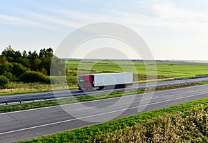 Truck with semi-trailer driving along highway on the sunset background. Goods delivery by roads. Services and Transport logistics