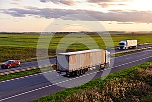 Truck with semi-trailer driving along highway on the sunset background. Goods delivery by roads. Services and Transport logistics