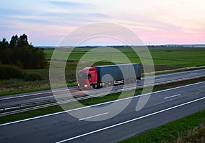 Truck with semi-trailer driving along highway on the sunset background. Goods delivery by roads. Services and Transport logistics