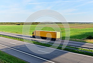 Truck with semi-trailer driving along highway on the sunset background. Goods delivery by roads. Services and Transport logistics