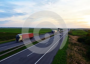 Truck with semi-trailer driving along highway on the sunset background. Goods delivery by roads. Services and Transport logistics