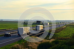 Truck with semi-trailer driving along highway on the sunset background. Goods delivery by roads. Services and Transport logistics