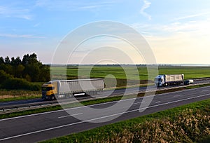 Truck with semi-trailer driving along highway on the sunset background. Goods delivery by roads. Services and Transport logistics