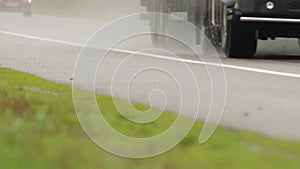 A truck with a semi-trailer is driving on a motorway wet from the rain, a close-up. Truck chassis, background. Copy