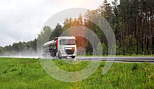 A truck with a semi-trailer tanker transports a dangerous cargo of fuel on a motorway slippery in the rain, industry