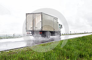 A truck with a semi-trailer transports cargo in the summer on a motorway in rainy weather. Copy space for text