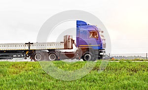 A truck with a semi-trailer transports cargo in the summer on a motorway in rainy weather. Copy space for text