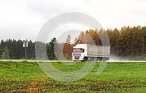 A truck with a semi-trailer transports cargo in the summer on a motorway in rainy weather. Copy space for text