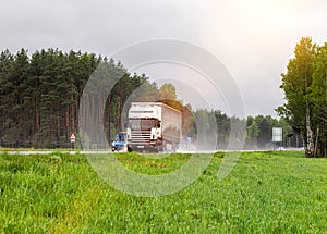 A truck with a semi-trailer transports cargo in the summer on a motorway in rainy weather. Copy space for text