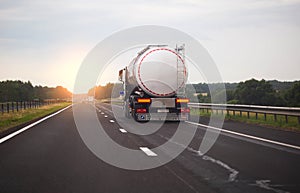A truck with a semi-trailer transports a dangerous chemical cargo in a tank car on a highway against the background of a