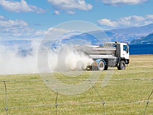 Truck spreading fertilizer on pasture meadow