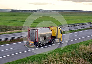 Truck with tank container driving along highway. International bulk gas and liquid transportation liquefied gas and cryogenic