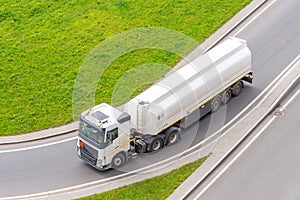 Truck with tank trailer and fuel turns on city highway, aerial view