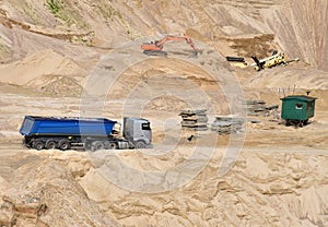 Truck with tipper semi trailer transported sand from the quarry. Dump truck and excavator working in open pit mine. Sand and