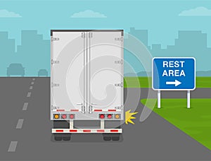 Truck is about to to turn right on highway. Heavy vehicle driving on motorways. Rest area road or traffic sign. Back view.