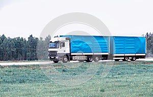 Truck tractor hitch with semi-trailer transports cargo on a country highway with a large tonnage and volume of cargo. Copy space photo