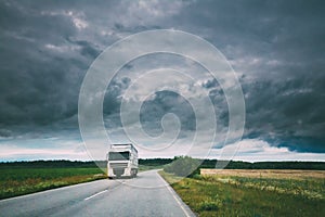 Truck, Tractor Unit, Prime Mover, Traction Unit In Motion On Country Road, Freeway In Europe. Cloudy Sky Above The