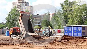 Truck and tractors work on construction site at summer day