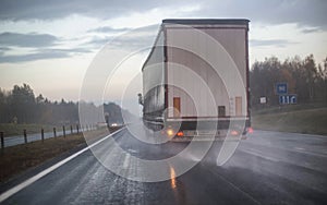 A truck with a trailer is being rebuilt on a motorway in a different row on slippery wet roads. The concept of security and