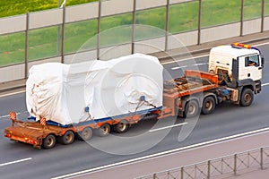 Truck with trailer and cargo covered with white cloth, tarpaulin. Rain protection