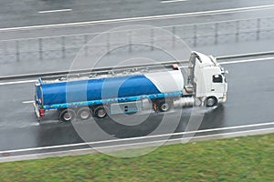 Truck with a trailer tank on the highway in during the rain bad weather.