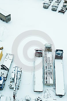 Truck under the snow. lorry covered with snow after snowfall. long trucks stand in a row aerial view. transportation concept. snow