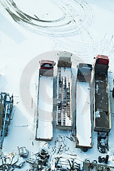 Truck under the snow. lorry covered with snow after snowfall. long trucks stand in a row aerial view. transportation concept. snow