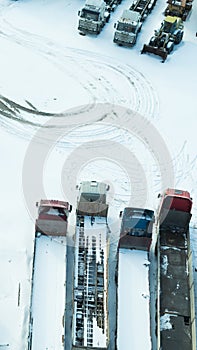 Truck under the snow. lorry covered with snow after snowfall. long trucks stand in a row aerial view. transportation concept. snow