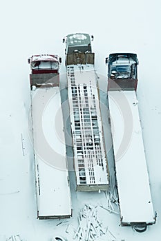 Truck under the snow. lorry covered with snow after snowfall. long trucks stand in a row aerial view. transportation concept. snow