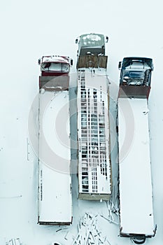 Truck under the snow. lorry covered with snow after snowfall. long trucks stand in a row aerial view. transportation concept. snow