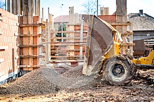 Truck unloading gravel with excavator and backhoe on construction site