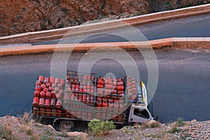 Truck with usual for north Africa red gasbags on Serpentine mountain road in Gorges Dades in high Atlas, Morocco