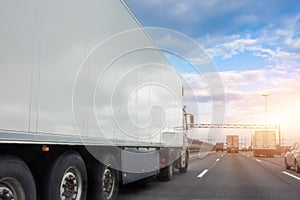 Truck with a white trailer drives along the highway in heavy traffic in the evening at sunset