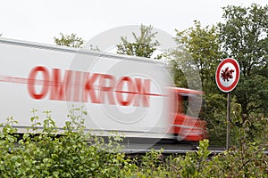 Truck with the word OMIKRON and a sign as symbol for covid-19 virus spreading by traveling and business photo