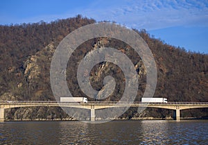 Trucks carrying goods cross the bridge over the water. Transport of goods