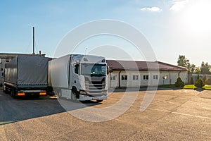 Trucks with containers in the parking lot along the highway against the background of clouds. The concept of logistics, transport