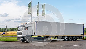 Trucks with containers in the parking lot along the highway against the background of clouds. The concept of logistics, transport