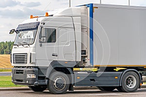 Trucks with containers in the parking lot along the highway against the background of clouds. The concept of logistics, transport