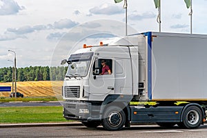 Trucks with containers in the parking lot along the highway against the background of clouds. The concept of logistics, transport