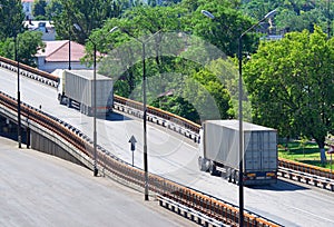 Trucks going up the bridge, cargo transportation, delivery and shipping concept, green trees on background