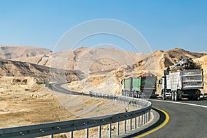 Trucks heading up on highway to the rocky mountains in the Negev desert. Road with tracks.