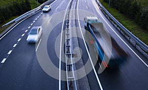 Trucks on a highway, motion blur, light trails. Night or evening shot of trucks doing transportation and logistics