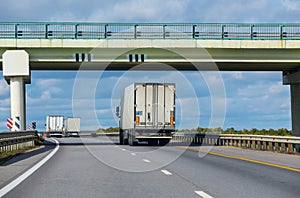 Trucks move under a viaduck.