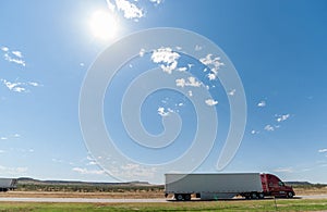 Trucks passing, mesa landforms on horizon beyond Landscape along