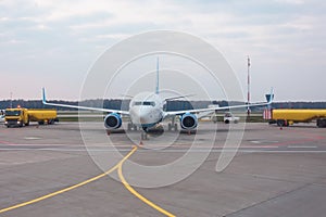 Trucks refueling trucks with trailers next to a passenger airplane