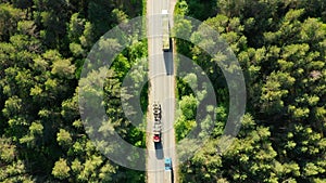 Trucks on road in coniferous forest, aerial drone