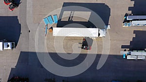 Trucks with semi-trailers stand on the parking lot of the logistics park with loading hub and wait for load and unload goods at